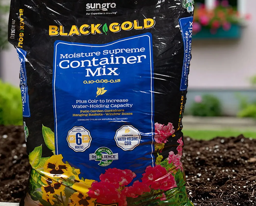 Sungro Black Gold Moisture Supreme Container Mix bag with blue label surrounded by flowering plants.