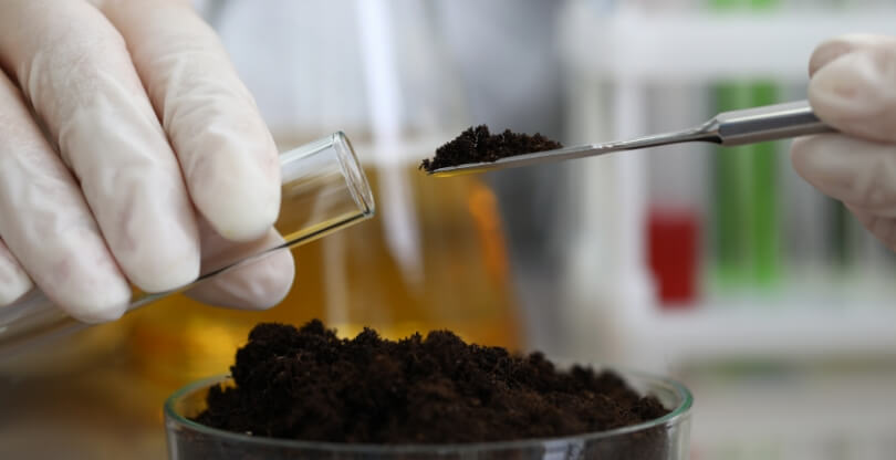 Scientist places soil in a beaker using a spoon like instrument